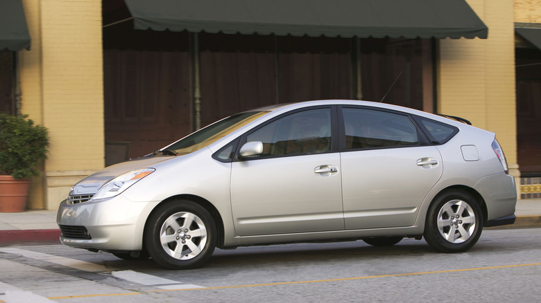 A silver Toyota Prius hybrid drives down a city street.