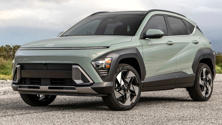 A 2026 light green Hyundai Kona parked on a quiet road with cloudy skies and open scenery in the background.
