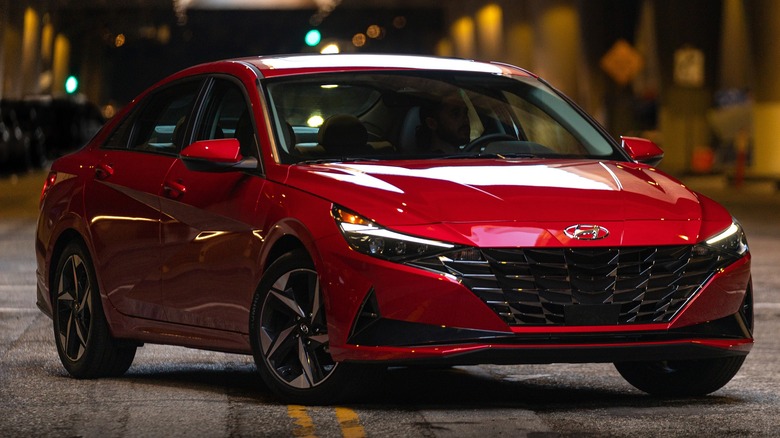 A 2026 red Hyundai Elantra positioned under an overpass with lights reflecting off its sleek body.