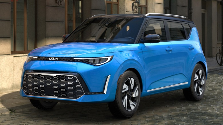 A 2024 blue Kia Soul parked along a cobblestone street outside a building.