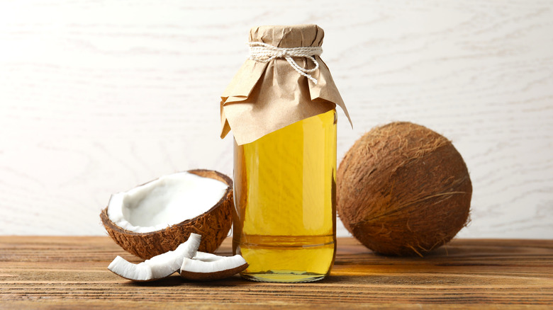 Coconut half next to a bottle of oil