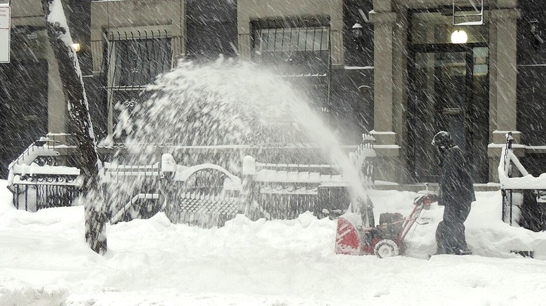 Person using a snow blower on a city sidewalk in 2016