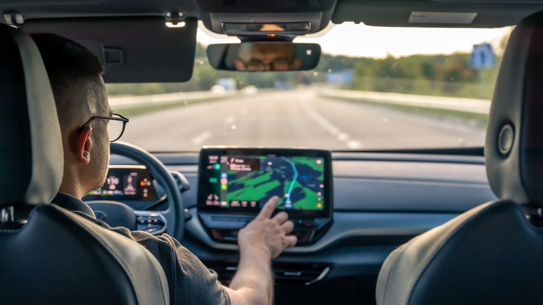 Person driving a car touching a GPS screen