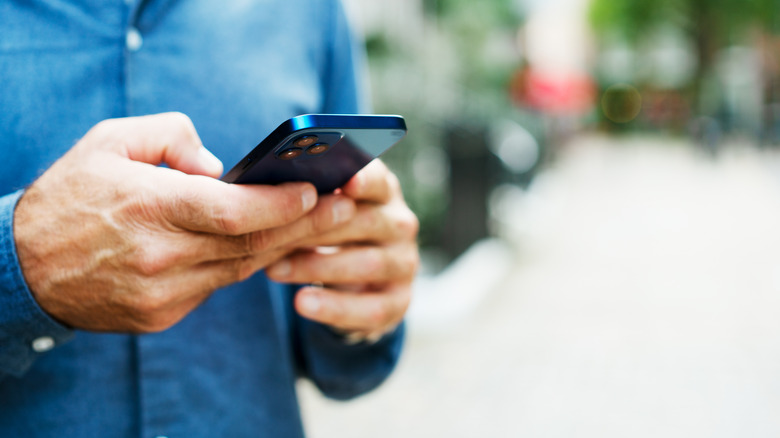 Person in blue shirt holding a smartphone