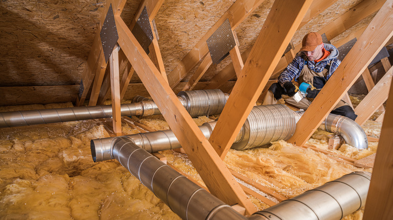 Person working on insulation and ducts in an attic