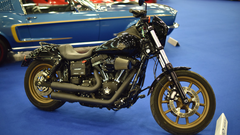 A black Harley-Davidson Low Rider S on display at a Sotheby's auction on a blue carpet.