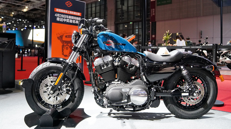 A blue Harley-Davidson Sportster motorcycle on display on a podium at an exhibition in Shanghai.