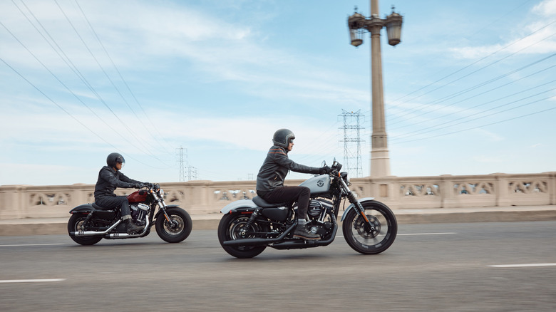 Two riders in full gear speeding down a road on Harley Iron 883s