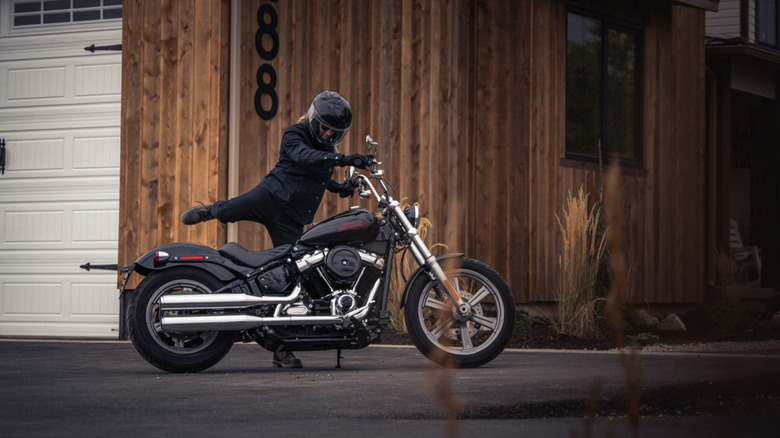 A fully kitted-out rider in the process of mounting a 2024 FXST softail standard