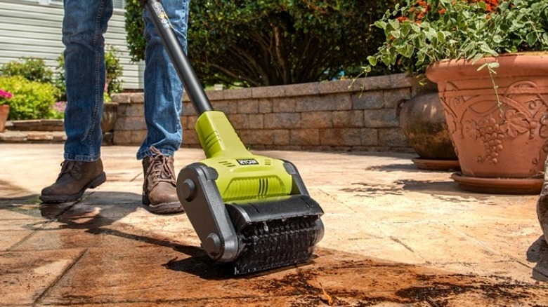 Person using a scrubbing tool on a patio