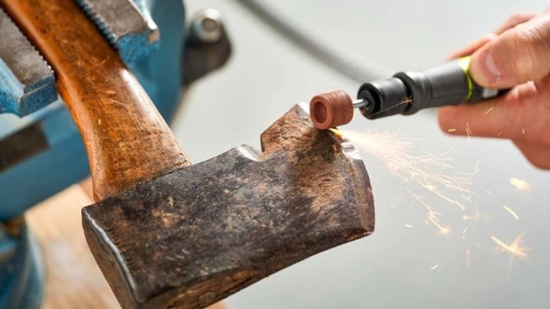 Hand using a rotary tool to sharpen an ax