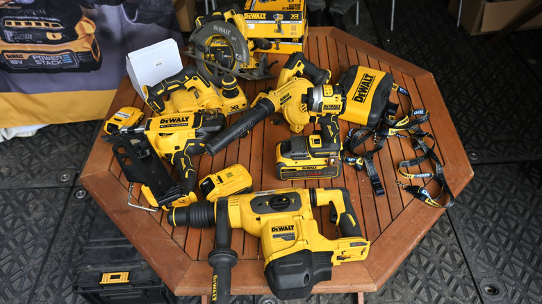 Various yellow and black DeWalt cordless power tools sitting on a wooden table.