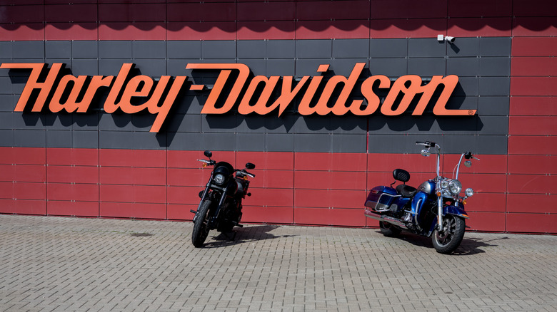 Two Harley-Davidson bikes parked in front of a red bick wall