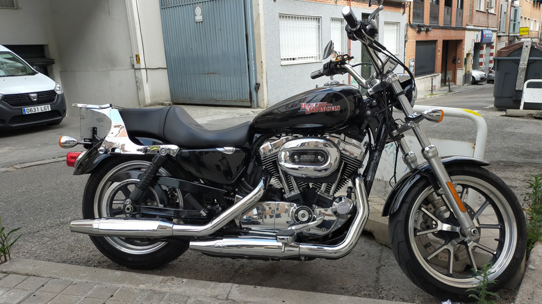 A black and silver Harley Sportster 1200 parked at the side of a street