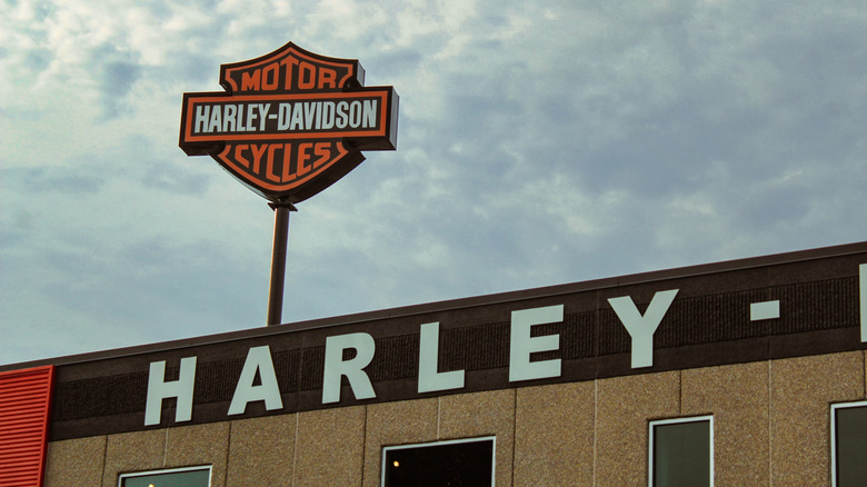 A Harley Davidson on a pole high above a dealer with the word "Harley" visible