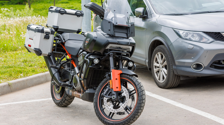 A gray Harley pan America 1250 parked next to a car in a designated zone