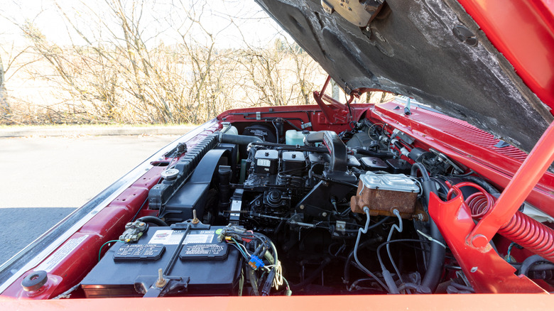 A red pickup truck with its hood open, revealing the engine