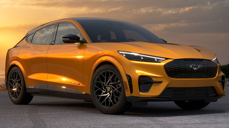 A parked orange Ford Mustang Mach-E against a sunset sky