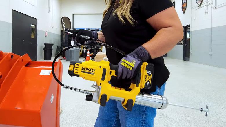 Person holding an electric grease gun in a shop