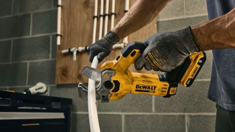 person cutting plastic tubing with tool