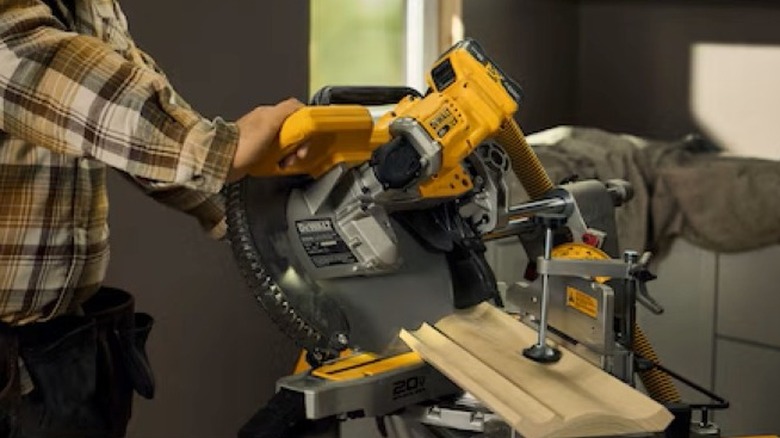 Person cutting baseboard with a miter saw