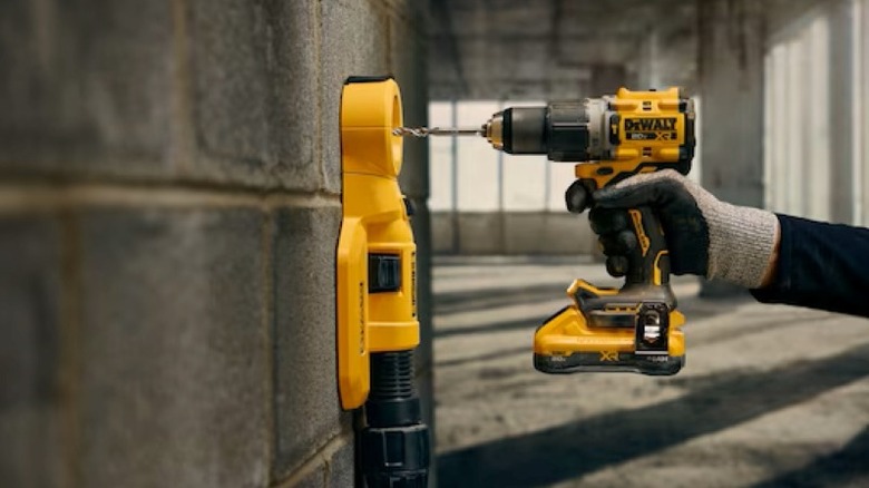 Person using hammer drill on cinder block wall