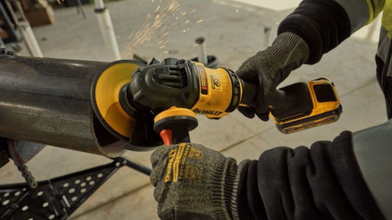 Person using grinder on cut end of a large pipe