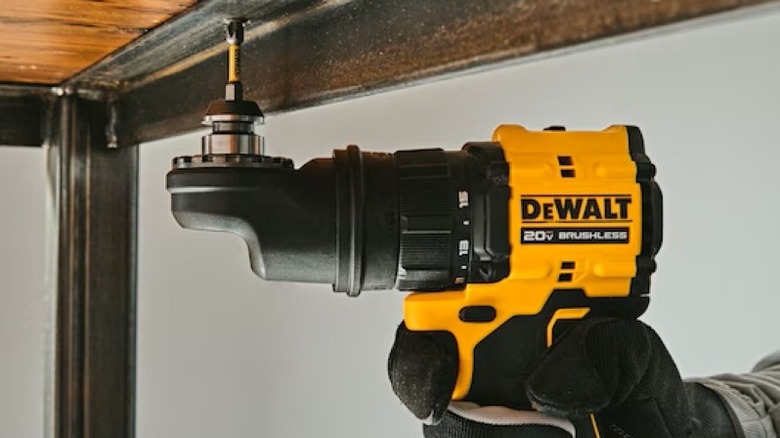 Person using right angle drill under a table