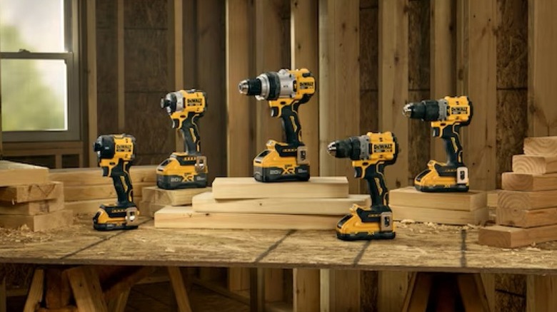 Several impact wrenches and drills on a plywood table