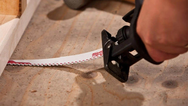A Milwaukee Sawzall blade cutting under a board