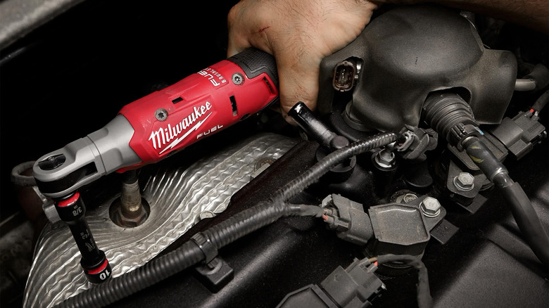 A person using a Milwaukee ratchet to tighten a bolt