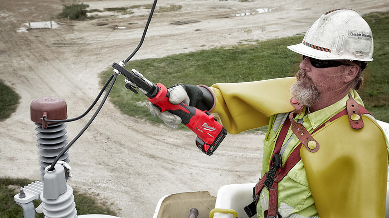 A man using utility crimpers on power line