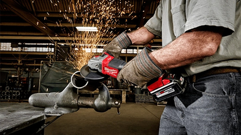 A man using an angle grinder on a piece of metal