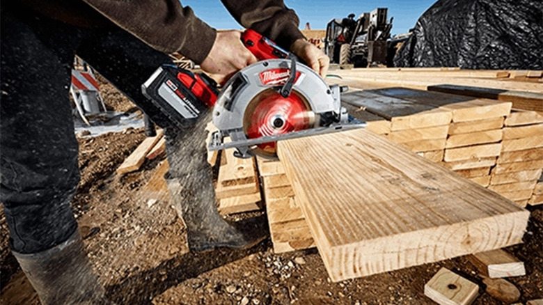 A man cutting a piece of wood with a circular saw