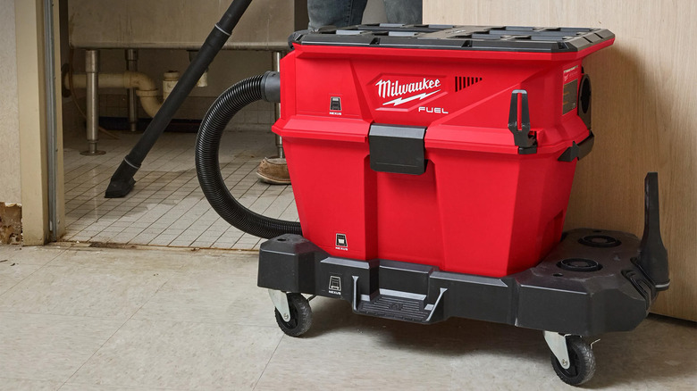 A person cleaning up a bathroom with a wet/dry vac
