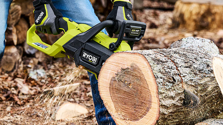 A person cutting a log with a Ryobi chainsaw.