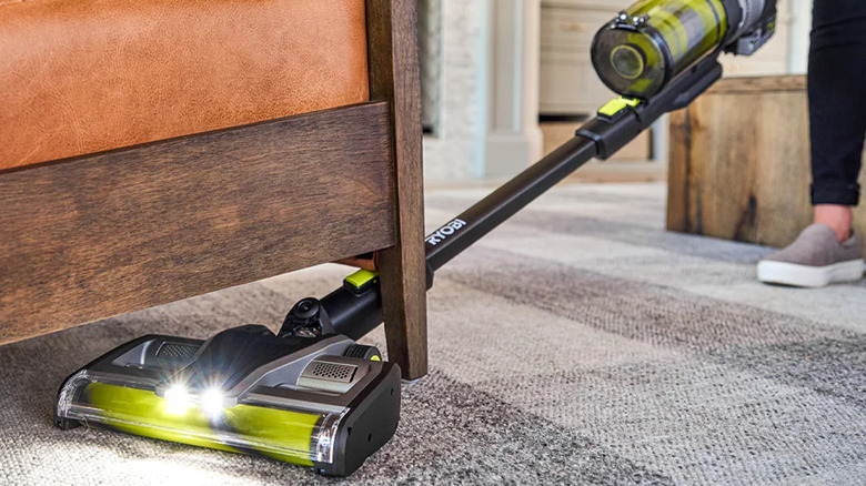 A Ryobi vacuum reaching under a nightstand.