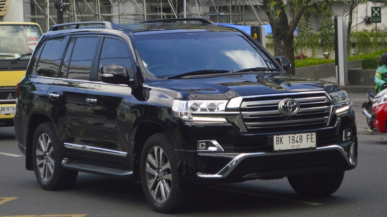 A black Toyota Land Cruiser from the LC200 generation moving down a road