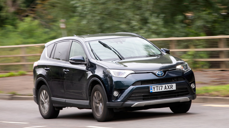 A black Toyota RAV4 from the X40 generation moving down the side of a road.