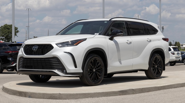 A 2023 Toyota Highlander in white parked outside in a lot on a sunny day