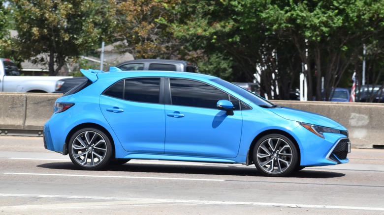 An electric blue Toyota GR Corollo moving at speed down an interstate highway