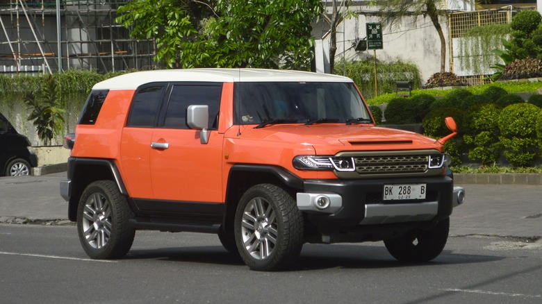 An orange and white Toyota FJ cruiser moving down a suburban road