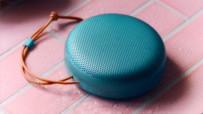 A teal Bang & Olufsen speaker on a brick table