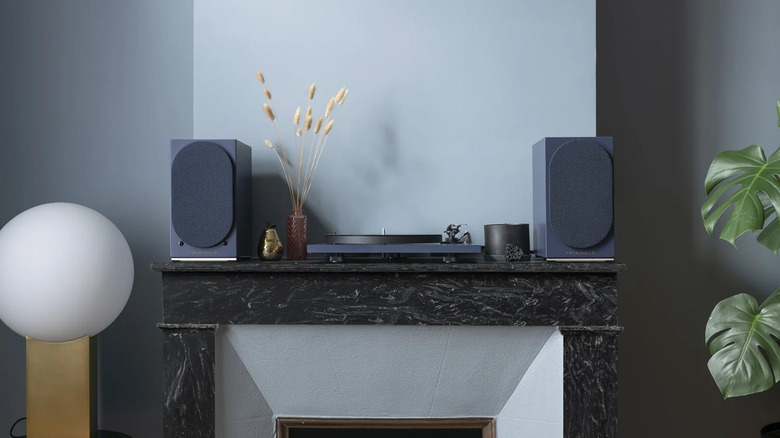 A pair of AIO Twin speakers on a mantle above a fireplace
