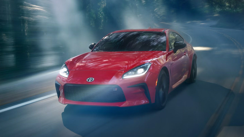 A red 2025 Toyota GR86 driving through a forest