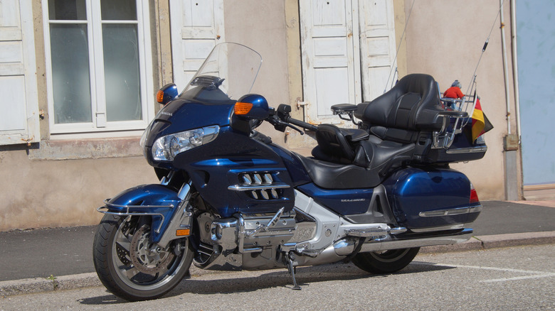 A dark blue Honda Gold Wing parked next to a building.