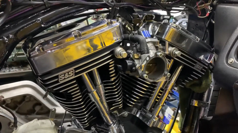 A zoomed in shot of the S&S T124 engine in silver while inside a workshop