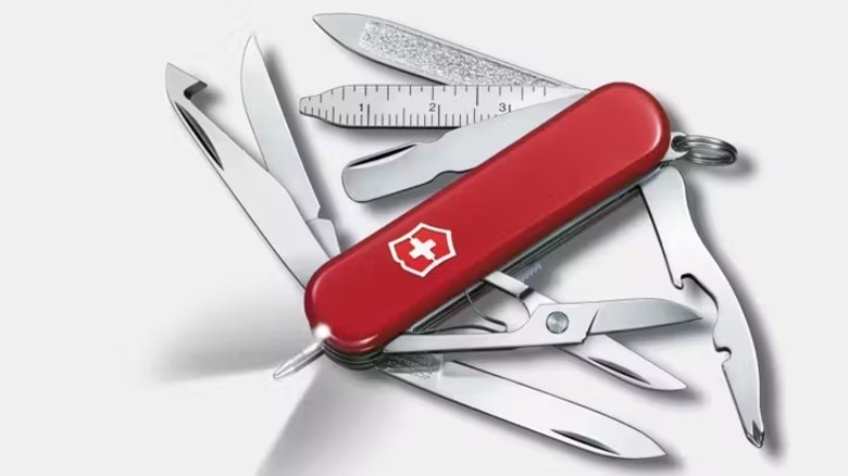 A red Victorinox Midnite Mini Champ Swiss Army knife with tools extended, including orange peeler