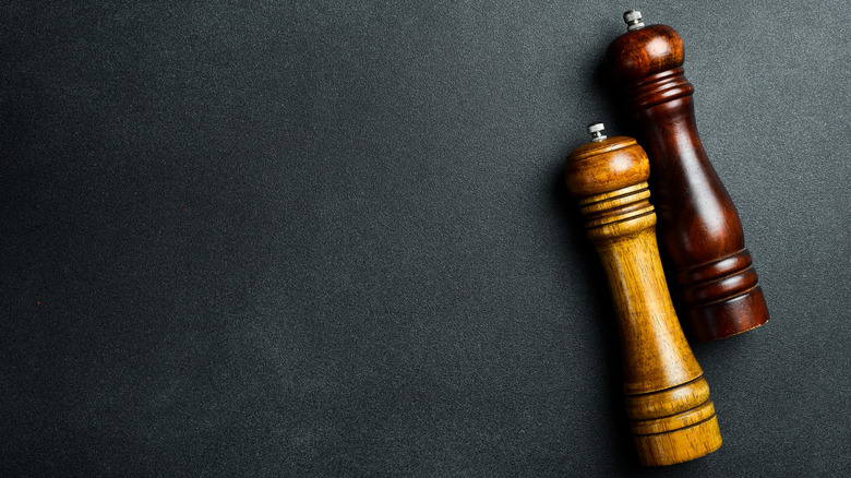 Wooden salt and pepper mills on a black backdrop