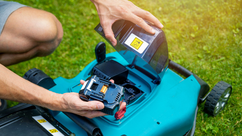 Person replacing battery in electric lawn mower